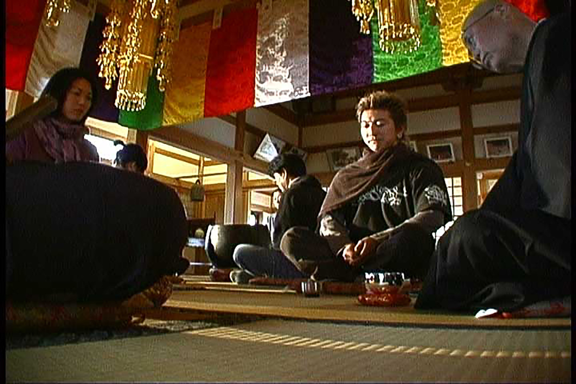 People in robes in a Zen Buddhist temple sitting on the floor.