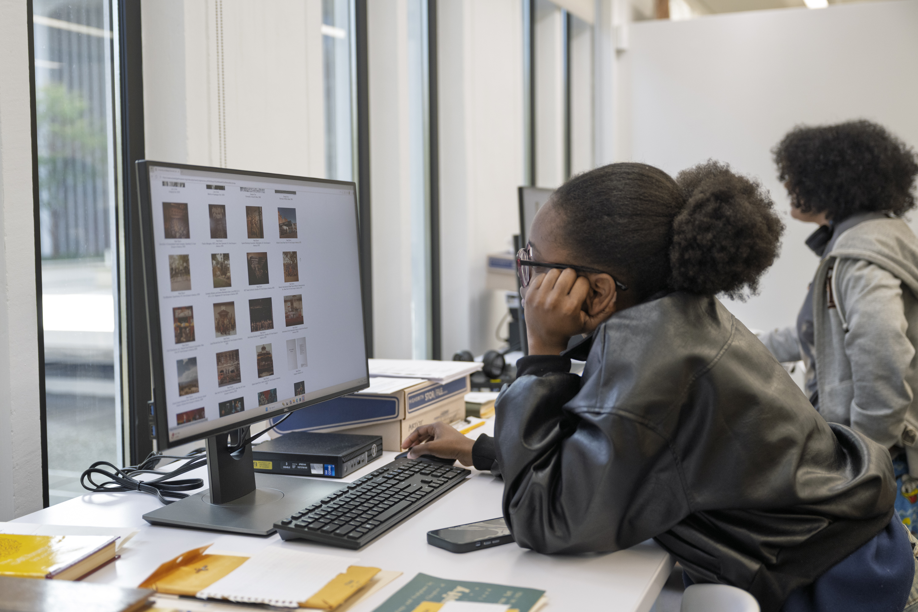 Two university students are browsing through the online database on the two research computers in the Collections Study Space. 
