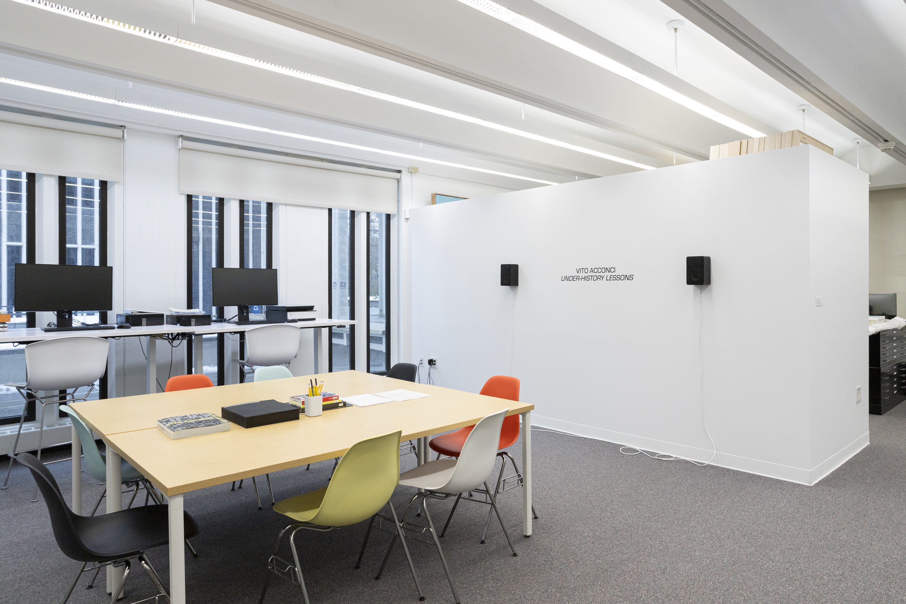 The installation Vito Acconci: Under-History Lessons in the Collections Study Space with a white wall and two mounted black speakers.
